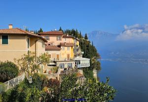 a building on a hill next to a body of water at Liver 203 in Tremosine Sul Garda