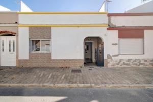 a white building with a blue door in a parking lot at Telmus Villa Rc D in Monte Gordo
