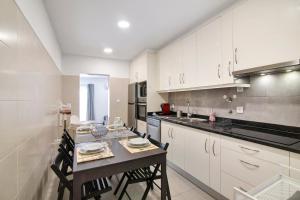 a kitchen with white cabinets and a table with chairs at Telmus Villa Rc D in Monte Gordo