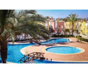 a large pool with two palm trees and buildings at Laguna beach Vera in Vera