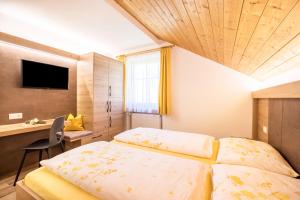 a bedroom with two beds and a desk and a television at Kuglerhof Apt 2 in Cadipietra