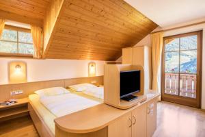a bedroom with a bed with a television on a desk at Kuglerhof Apt 2 in Cadipietra