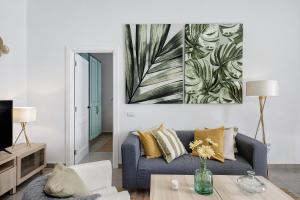 a living room with a blue couch and a painting on the wall at Urban Park Aloe in Los Llanos de Aridane
