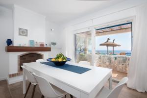 a white dining room with a table and a view of the ocean at Villa Domus Alba A - B in Felanitx