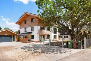 a house with a tree and two trash cans at Ferienwohnung Wendelsteinblick in Bad Tölz