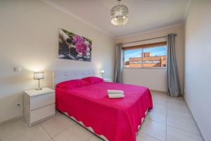 a bedroom with a pink bed and a window at Paraíso da Rocha in Portimão
