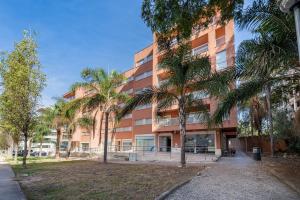 an apartment building with palm trees in front of it at Paraíso da Rocha in Portimão