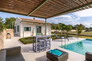 a patio with a table and chairs next to a swimming pool at Sa Verdal in El Port de la Selva
