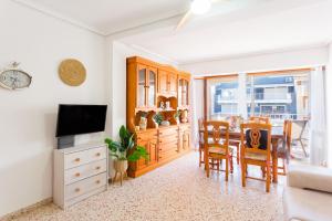 a living room with a television and a dining room at Palmera Beach House in Cullera