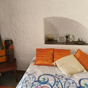 a bed with orange pillows on top of it at Cueva de Manuel in Guadix