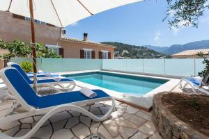 a villa with a swimming pool and two chairs and an umbrella at Casa Paqui in Port de Soller