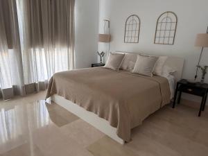 a white bedroom with a large bed and two windows at Apartamento Puerto Sotogrande in Sotogrande