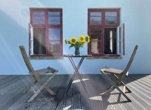 two chairs and a table with a vase of sunflowers at Projektraum Obst und Sterne in Rensow +8 photos