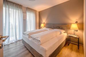 a bedroom with a large white bed with two lamps at Lores Loft in Merano