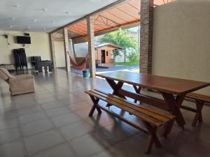 a dining room with a wooden table and a bench at Casa com piscina em Maringá in Maringá