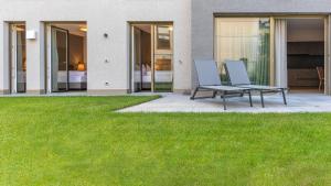 a patio with two chairs and a table on a lawn at Lores Loft in Merano