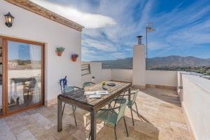 a patio with a wooden table and chairs on a balcony at Casa El Valle Verde Granada in Lecrin