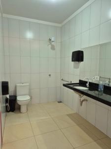 a white bathroom with a toilet and a sink at Casa com piscina em Maringá in Maringá