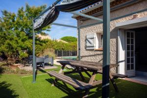 a picnic table and an umbrella in a yard at Maison Roxane in Six-Fours-les-Plages