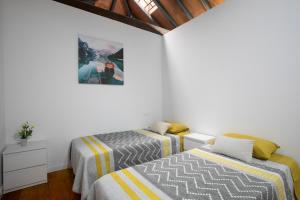 two beds in a room with white walls and wooden ceilings at Casa Rural tacoronte in Tacoronte