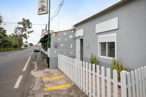 a building with a white fence next to a street at Casa Rural tacoronte in Tacoronte
