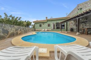 a swimming pool with two chairs and a house at Casa Rural Tijoco in Adeje
