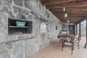 a room with a stone wall with a table and chairs at Casa Rural Tijoco in Adeje