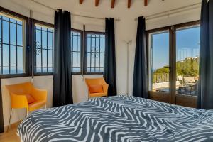 a bedroom with a bed with orange chairs and windows at Villa Amalia in Denia +36 photos