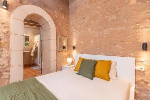 a bedroom with a white bed and a stone wall at Casa Groc in Costitx