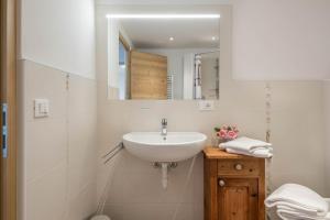 a white bathroom with a sink and a mirror at Nigglhof Apartment Katarina in Redagno +9 photos