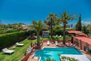 a backyard with a swimming pool and palm trees at Villa Tessa in Marbella