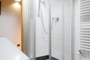 a shower in a bathroom with white tiles at Il sole di calde Lago Maggiore 505 in Castelveccana +16 photos