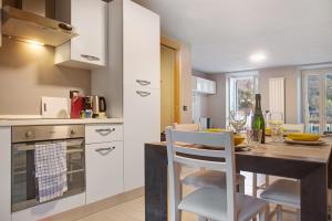 a kitchen with white cabinets and a table with chairs at Il sole di calde Lago Maggiore 505 in Castelveccana