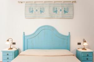 a bed with a blue headboard and two night stands at Piccola casa Marina in Villa San Pietro