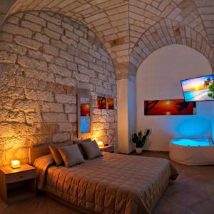 a bedroom with a large bed in a stone wall at Salento Houses & Idro Suites in Nardò