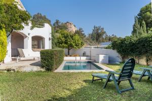 a yard with a pool and two chairs at Apartamentos Villa Martinez in Salobreña