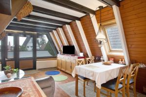a dining room with a table and a tv at Nurdach-Haus Typ 7 in Immenstaad am Bodensee