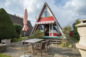 a small house with a table and an umbrella at Nurdach-Haus Typ 7 in Immenstaad am Bodensee