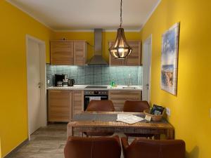 a kitchen with yellow walls and a wooden table and chairs at Ferienhaus Pirol in Zossen