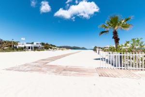 a boardwalk on the beach with a palm tree at Appartamenti Cavour H in Villasimius