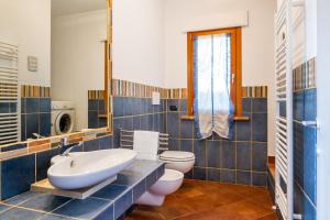 a blue tiled bathroom with a sink and a toilet at Villa Glicine - Colleberto in Follonica +25 photos