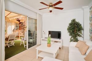 a living room with a white couch and a ceiling fan at Terrazas del Duque Beach Apartment in Adeje