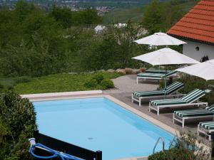 a swimming pool with two lawn chairs and umbrellas at Ferienhaus Straubehof in Sasbachwalden