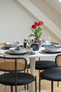 a white dining table with black chairs and red flowers at Cityloft für Stilvolle in Dessau +9 photos