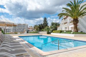 a swimming pool with lounge chairs next to a building at Apartamento Poseidonia in Felanitx