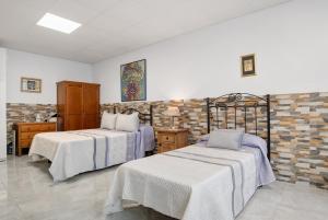 a bedroom with two beds and a brick wall at Loft Los Olivos in Algar +14 photos