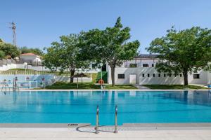 a large swimming pool with blue water in front of a building at Loft Los Olivos in Algar