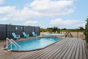 a swimming pool with two blue chairs on a wooden deck at Maison Boyardville Piscine in Saint-Georges-dʼOléron