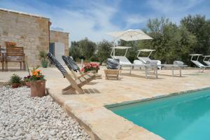 a patio with chairs and an umbrella next to a pool at Trullo Delori with infinity Pool in Villa Castelli
