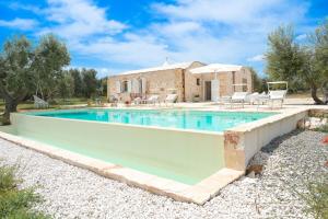 a swimming pool in front of a brick house at Trullo Delori with infinity Pool in Villa Castelli